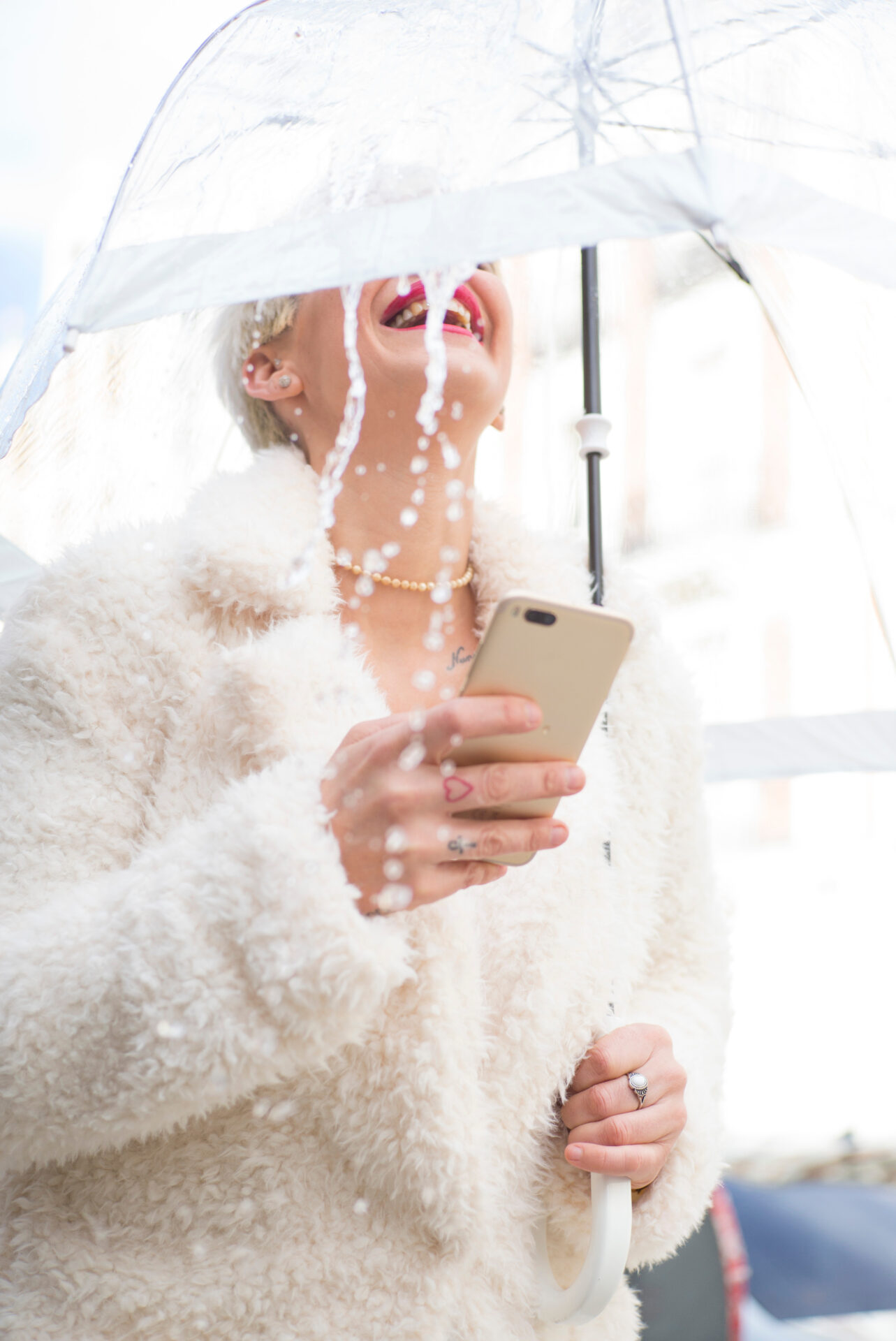Blonde woman with umbrella texting on smartphone Blonde woman with umbrella texting on smartphone
